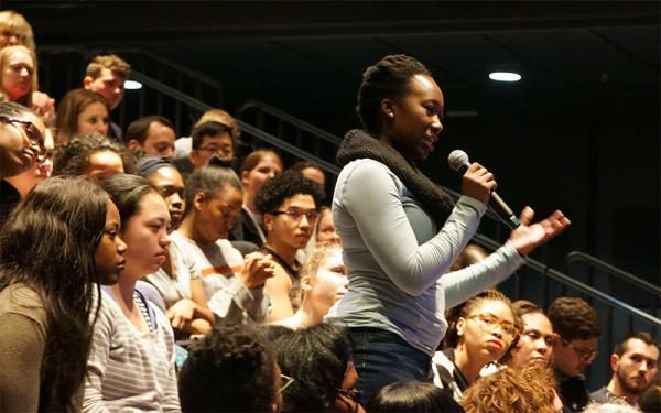 Woman asking question with microphone in hand, in audience