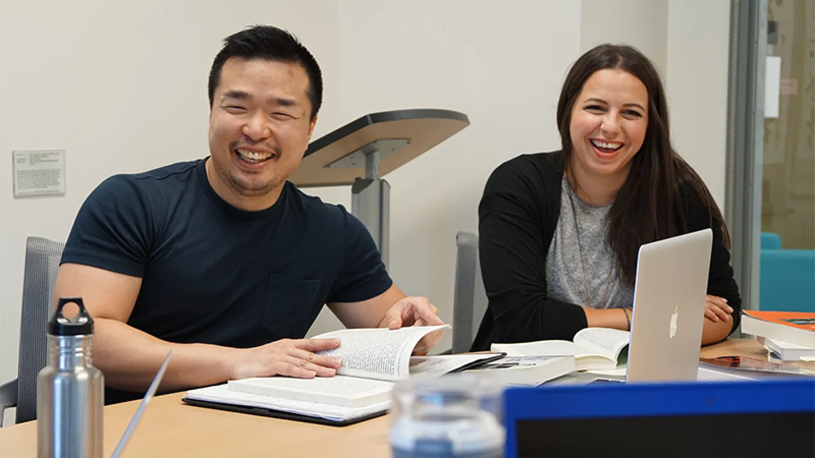 Two adults laughing at a desk