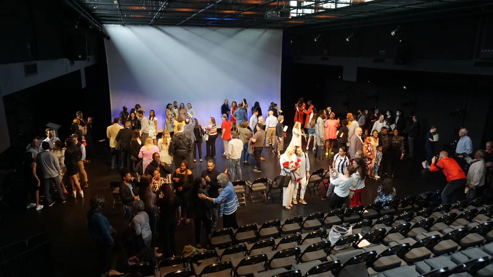 Audience gathers on stage to congratulate students