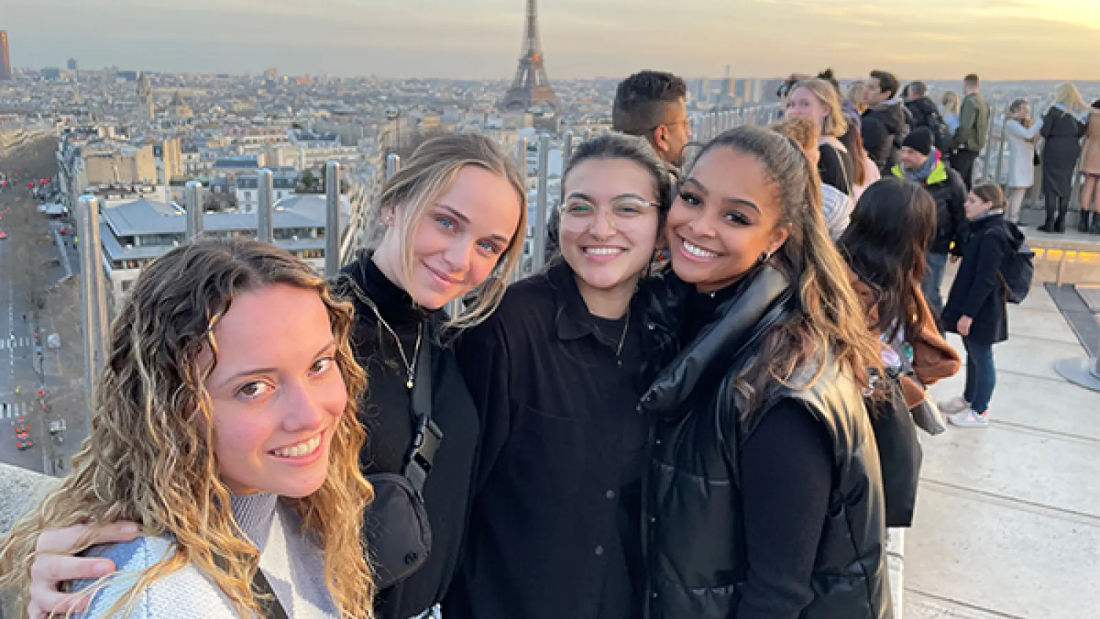 Women on top of building with Eiffel Tower in background. 