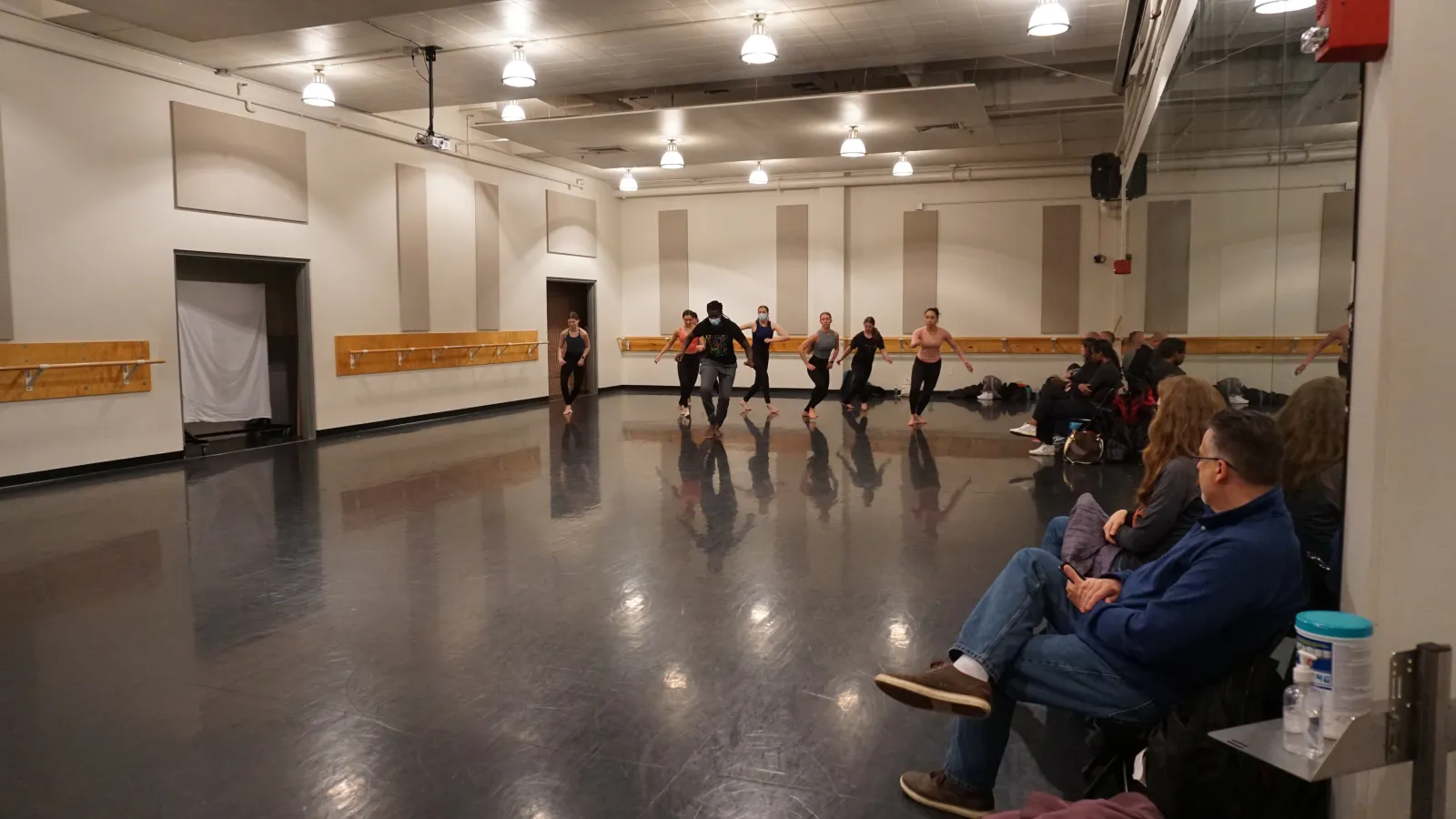 Dancers rehearsing in a studio with an audience