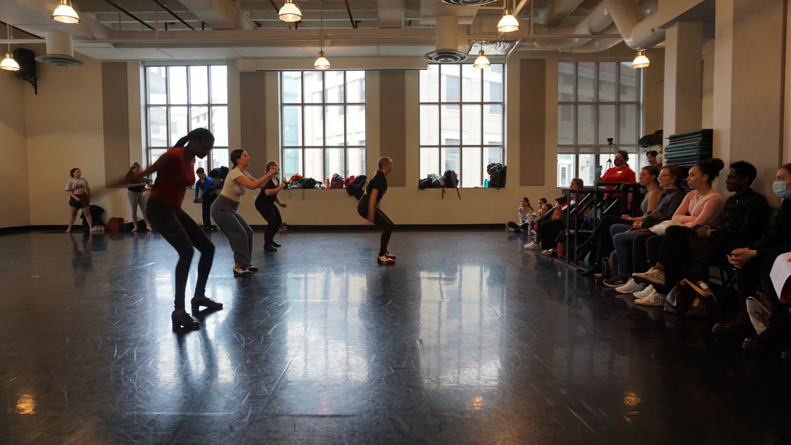 Dancers rehearsing in a studio with an audience