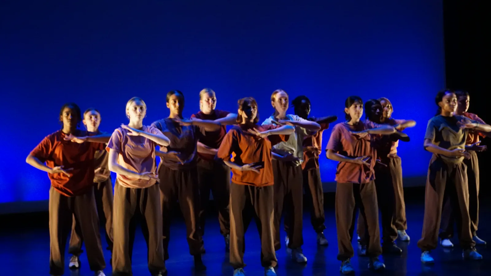 Dancers performing in front of blue scrim