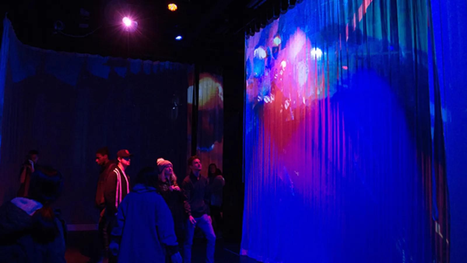 Audience looking at digital image on white scrim in dark room
