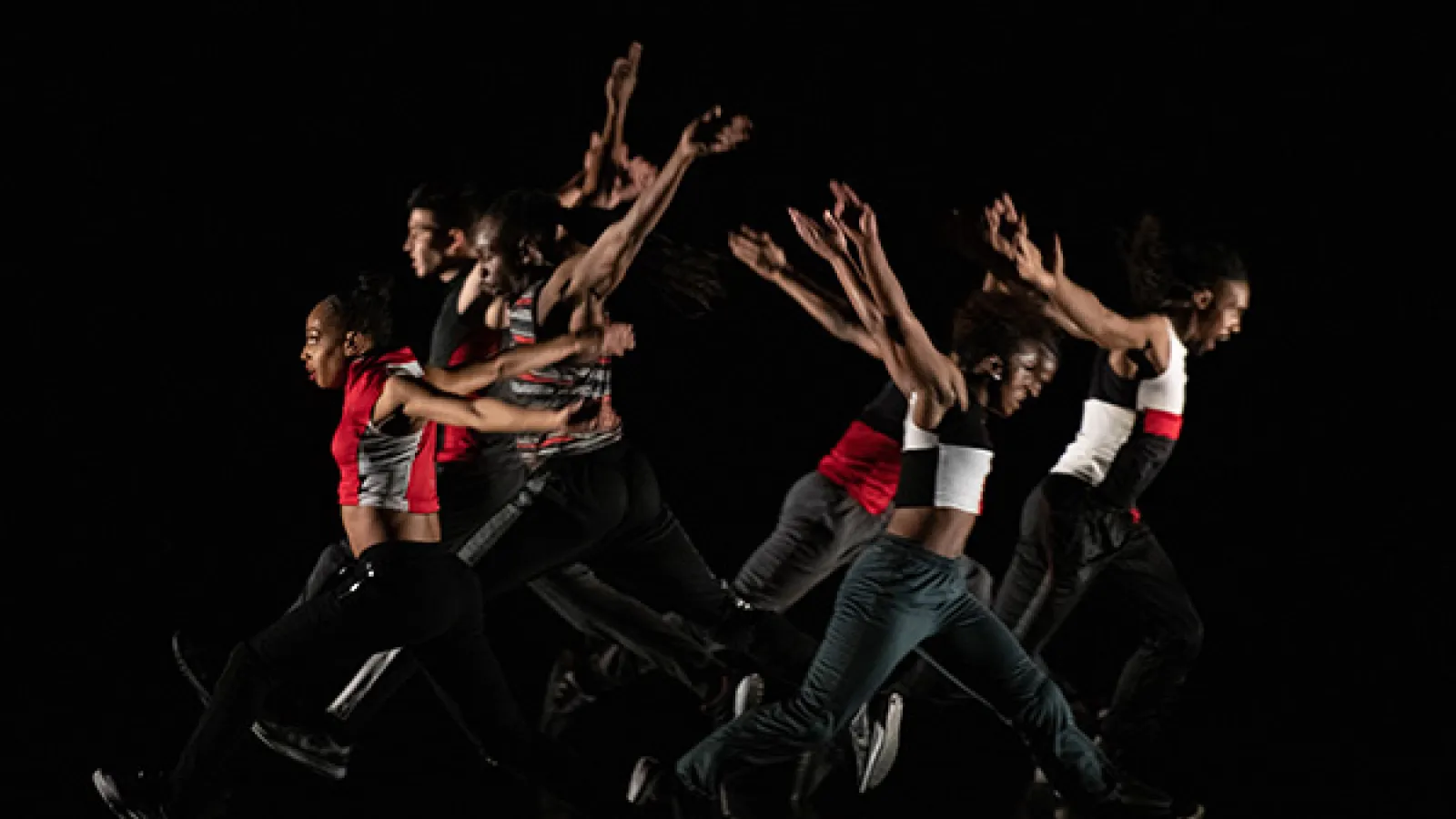 Dancers leaping wearing red, black and white costumes