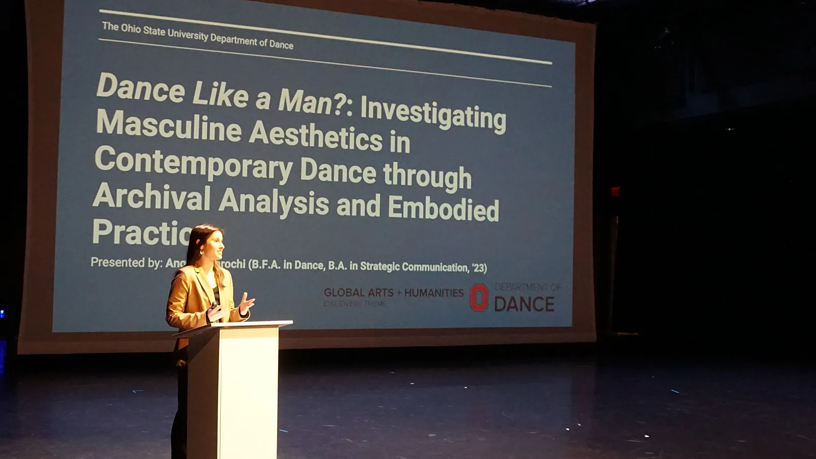 Woman standing at a podium in front of projection 