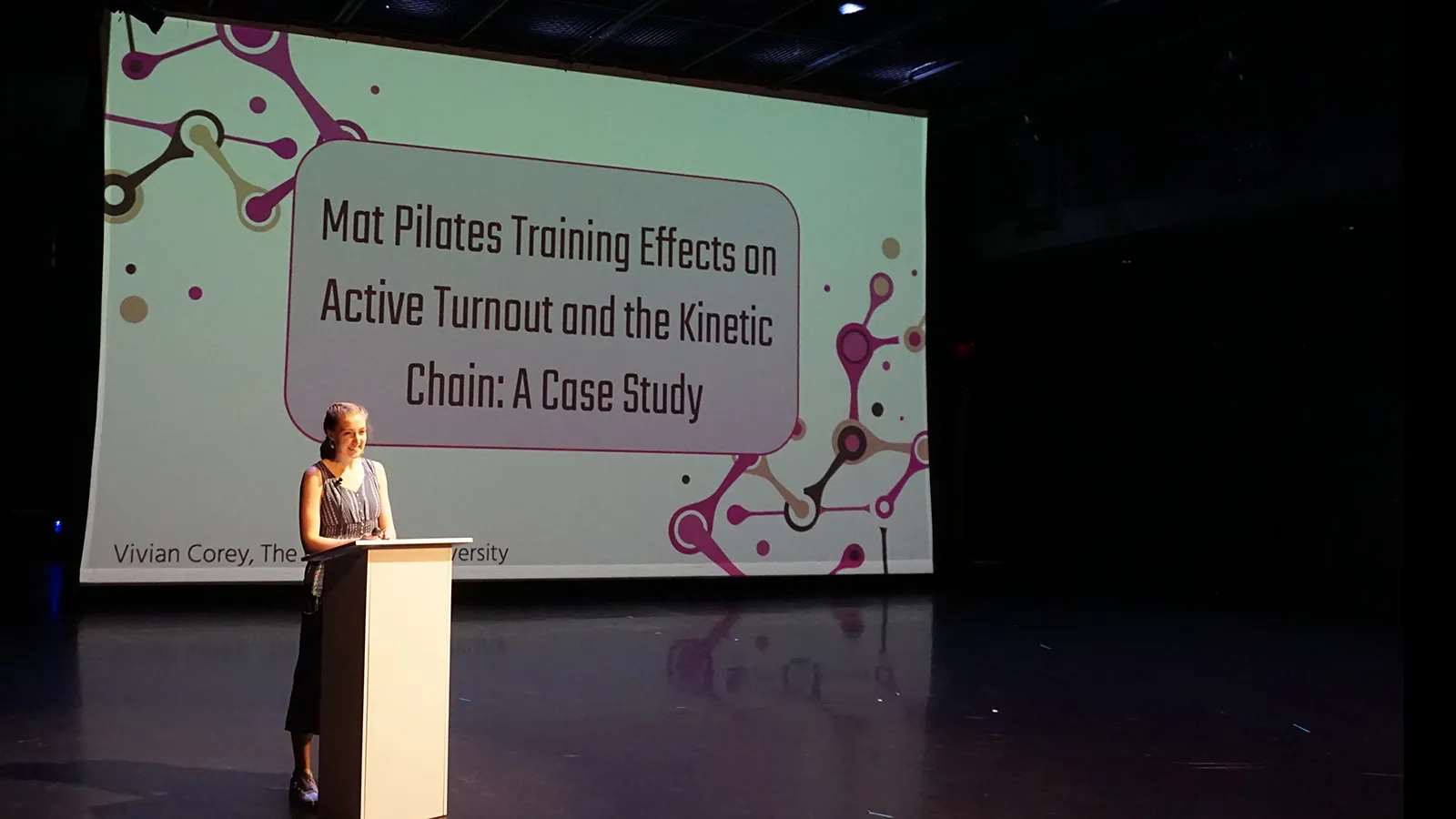 Woman standing at a podium in front of projection 