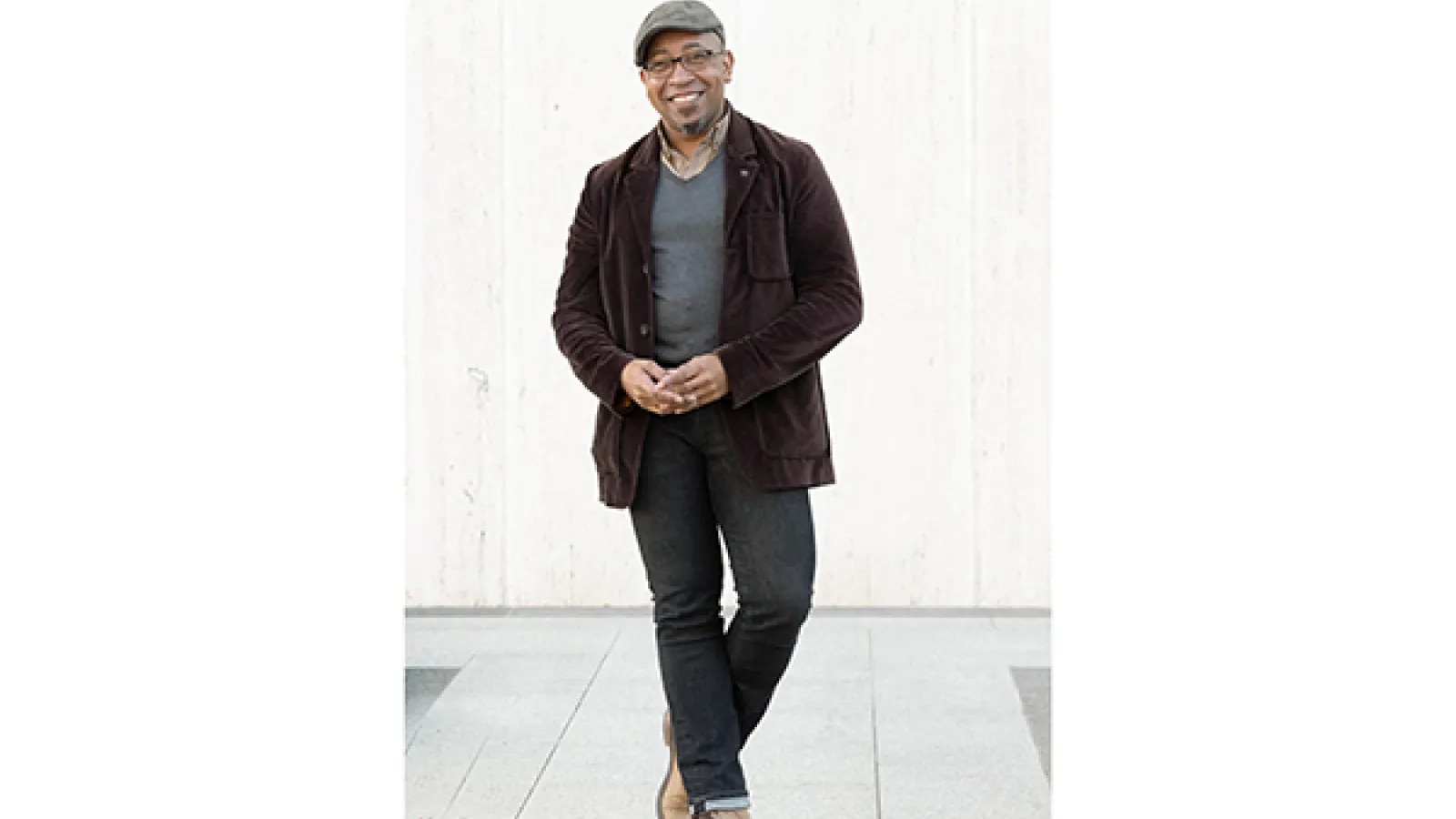 a person wearing a hat, brown suit coat and blue jeans