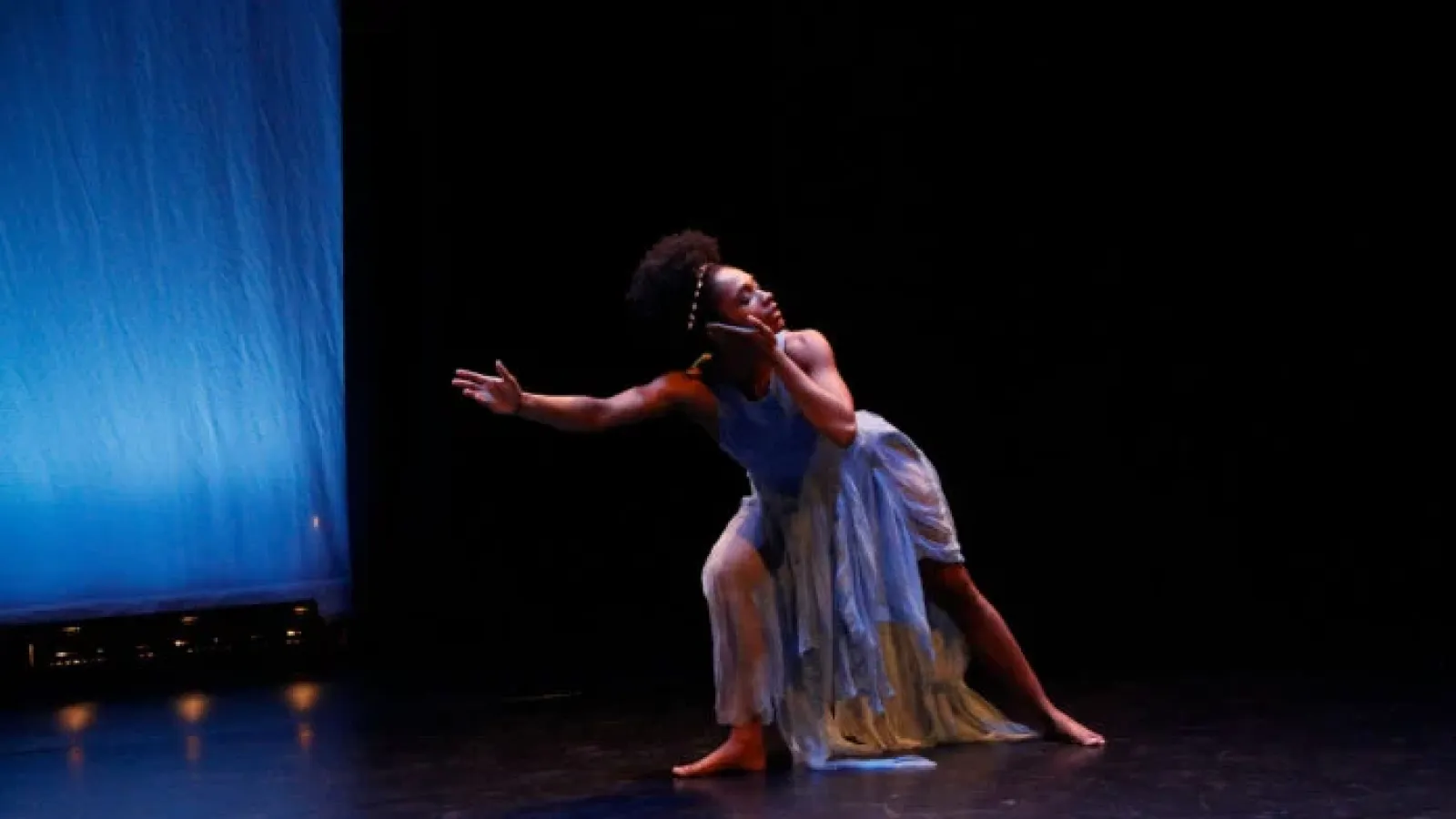 Dancer in blue costume leaning left toward blue screen