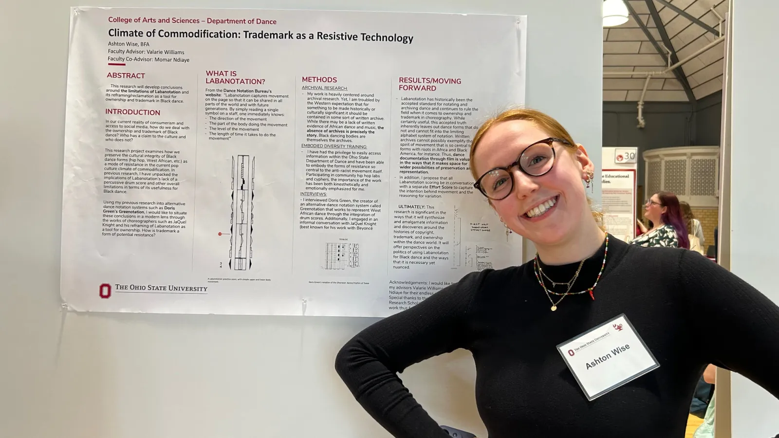 Student posing with research poster.