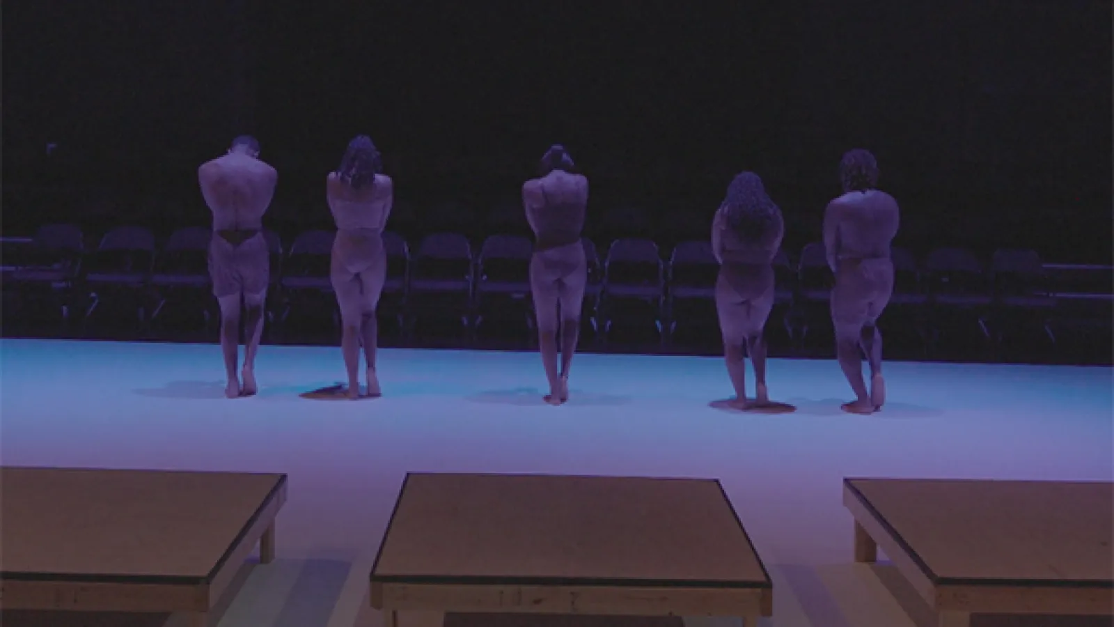 Dancers facing chairs in a theatre