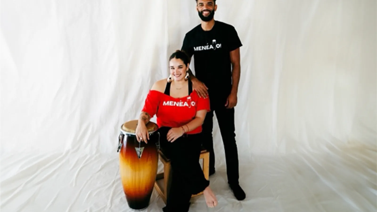 Person with red shirt sitting next to person standing in black shirt