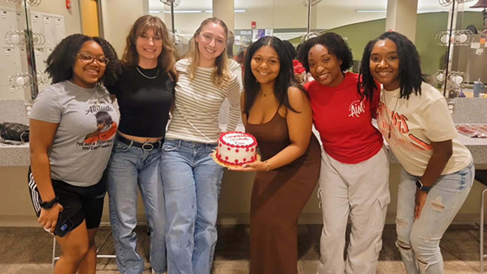 A group of people standing in front of a mirror with a cake