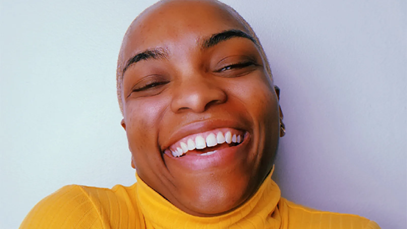 A headshot of a person wearing a yellow sweater