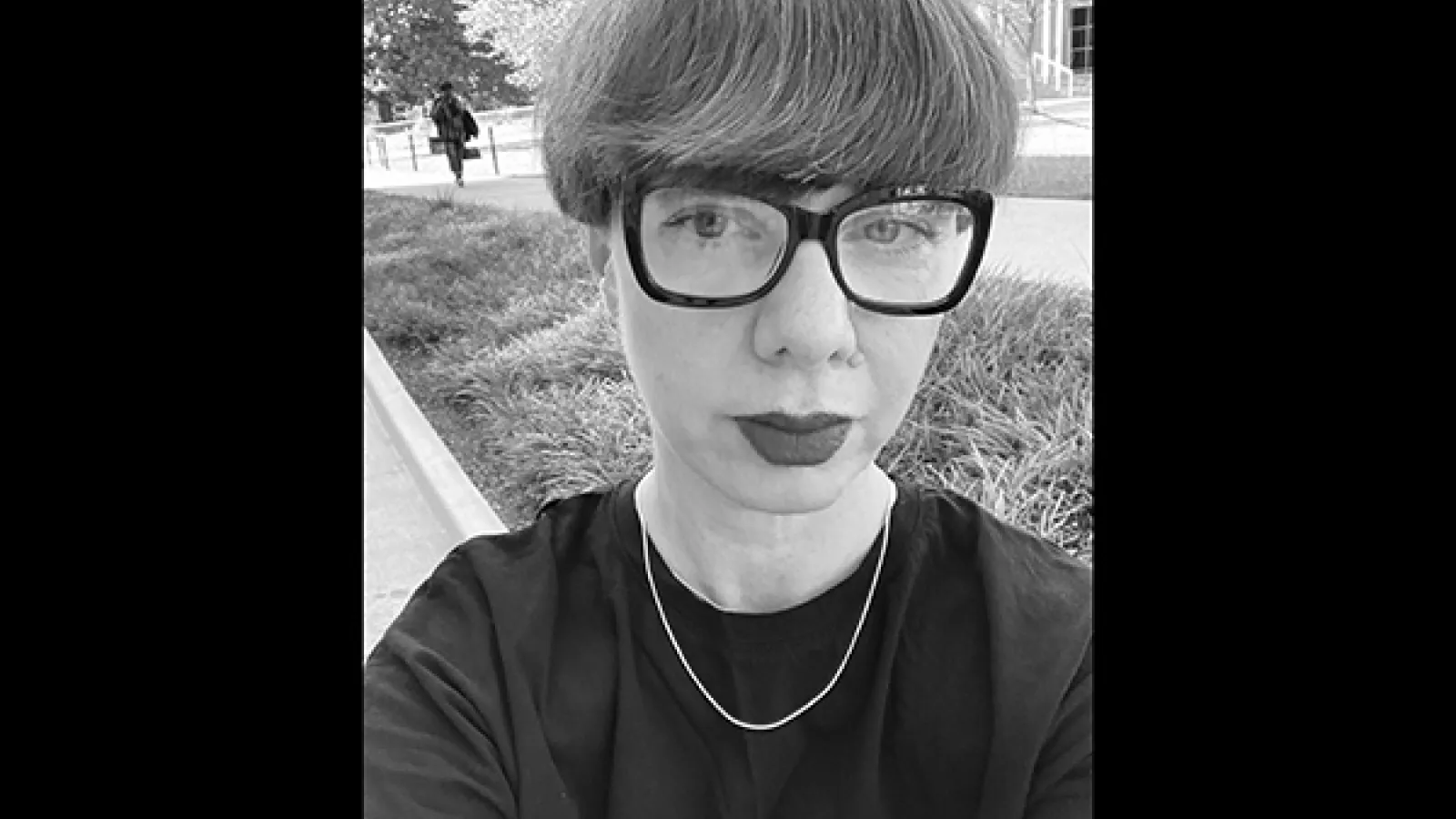 black and white photo of person with short hair and black glasses