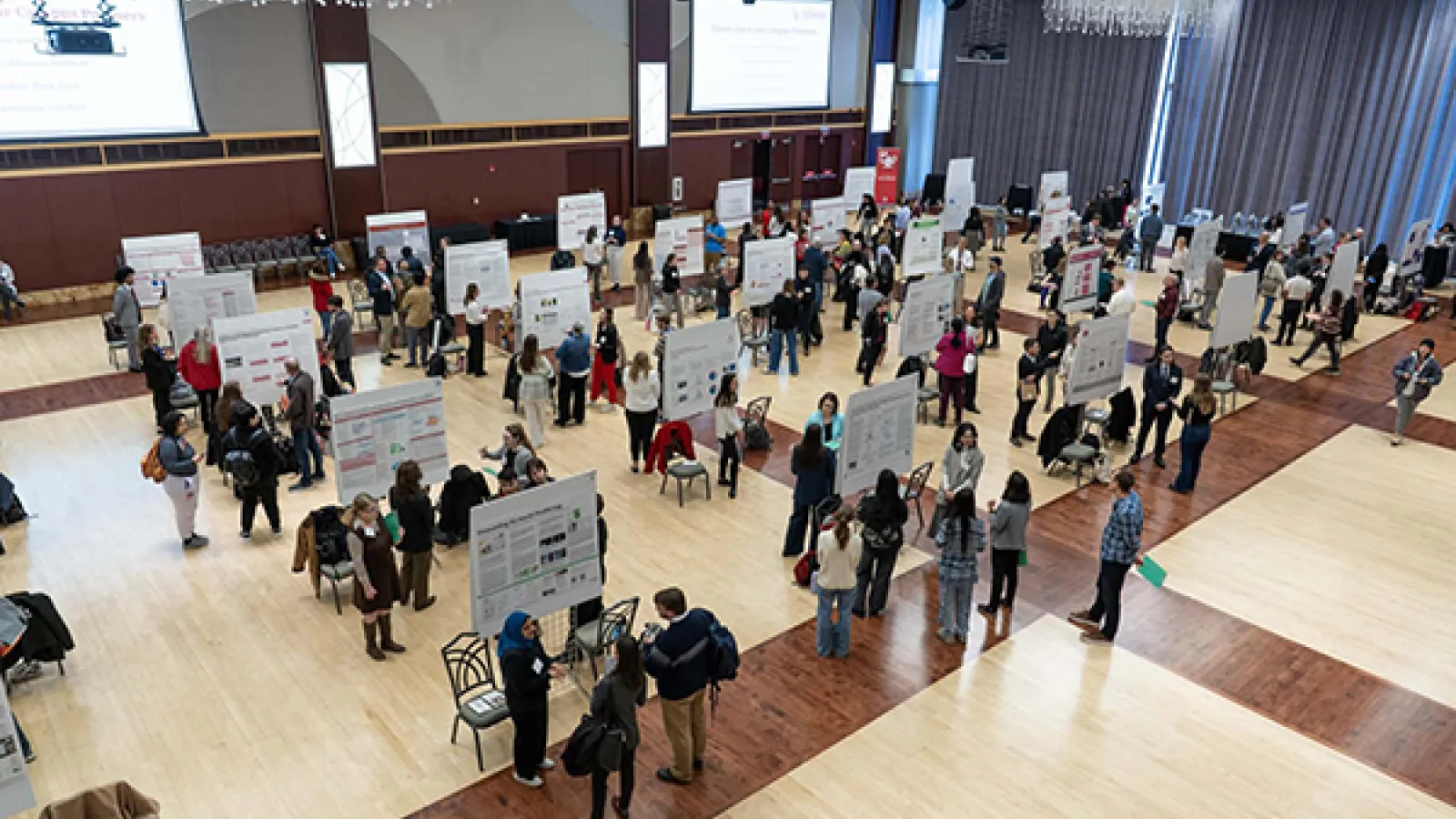Group of people standing next to posters in a large ballroom 