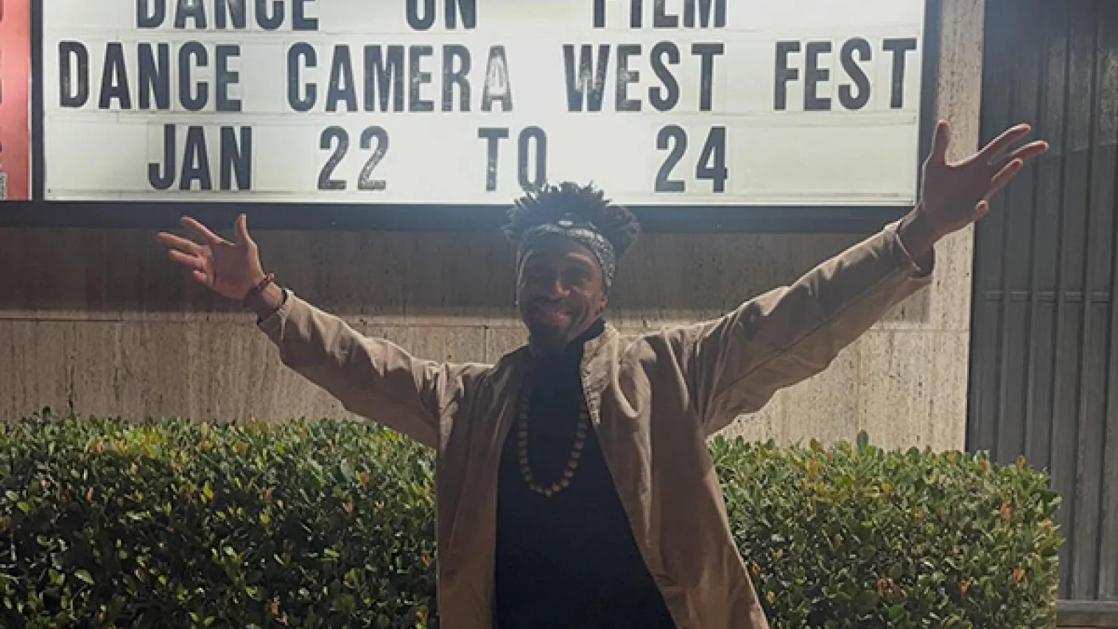 A man raising his arms in front of a sign