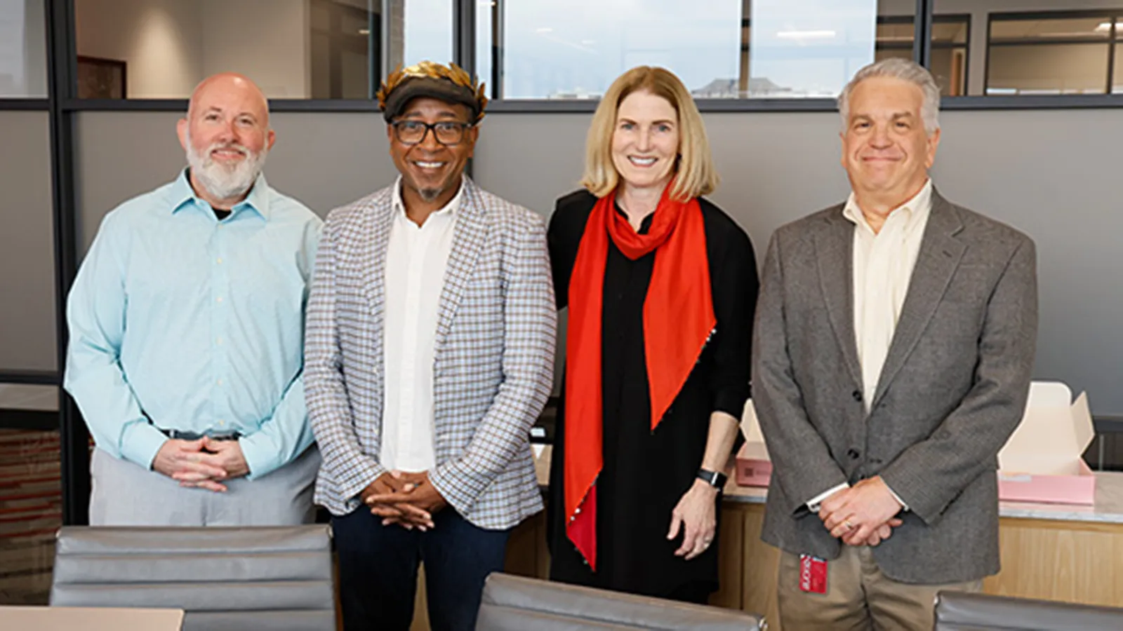 Four people posing for a photo in an office