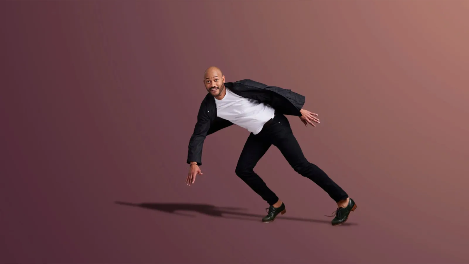 man wearing white shirt under black shirt with black pants and tap dance shoes leaning to the left