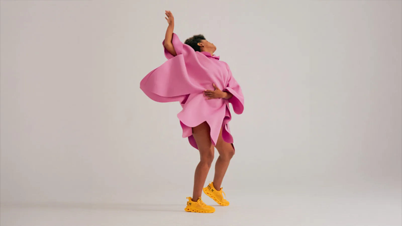 A woman wearing pink clothing and yellow sneakers dancing 
