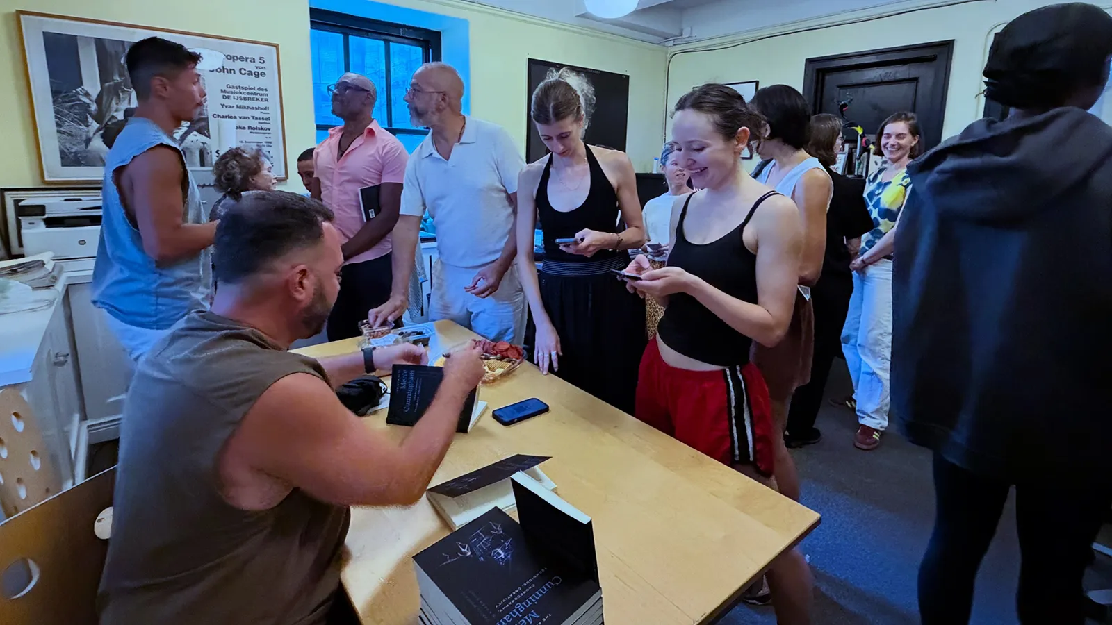 Person signing books at a table with a group of people standing in line