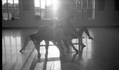 Dancers performing in a studio with sun coming in a window behind them