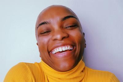 A headshot of a person wearing a yellow sweater