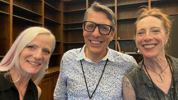 3 people posing for a photo in front of a bookcase