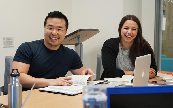 Two adults laughing at a desk