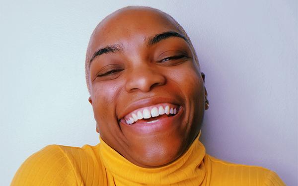 A headshot of a person wearing a yellow sweater