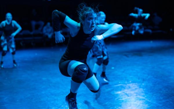 a dancer jumping on a blue lit stage