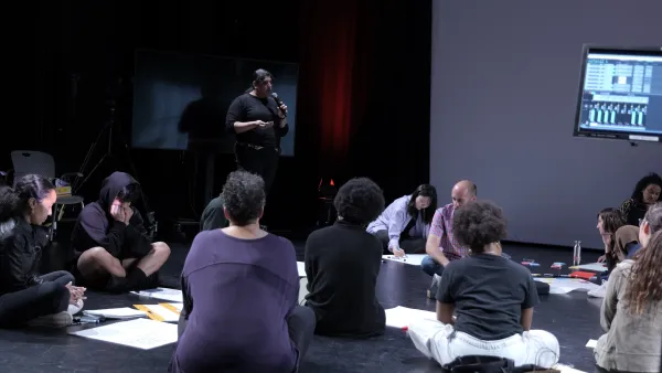 a person speaking to a people sitting on the floor