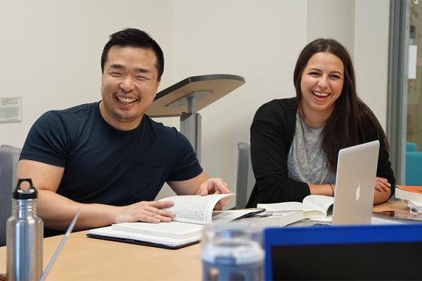 Two adults laughing at a desk