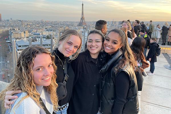 Women on top of building with Eiffel Tower in background. 