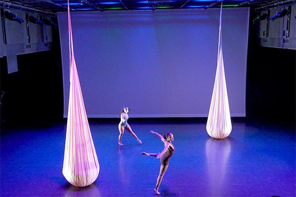 Dancers performing on a stage with hanging fabric