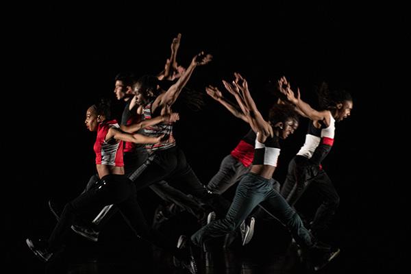 Dancers leaping wearing red, black and white costumes