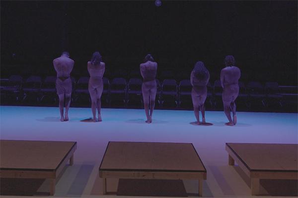 Dancers facing chairs in a theatre