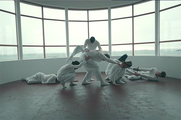 Dancers dressed in white in front of a large window