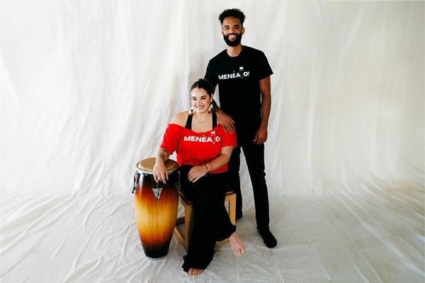 Person with red shirt sitting next to person standing in black shirt
