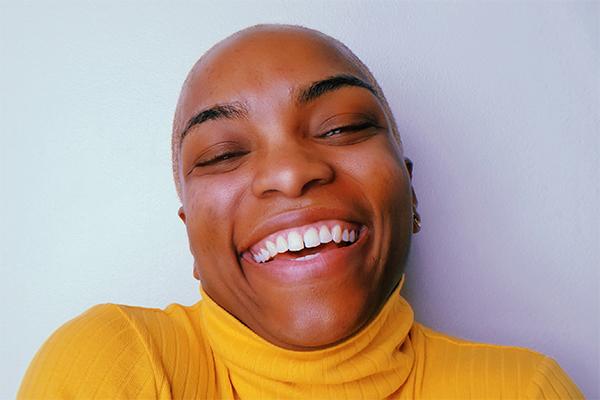 A headshot of a person wearing a yellow sweater