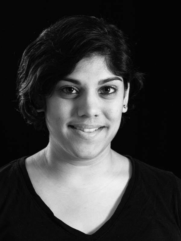 black and white image of a south asian woman with short black hair looking at the camera with a soft smile