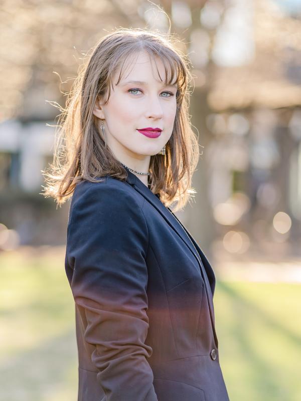 A brown-haired woman wearing a blazer looks at the camera with a slight smile.