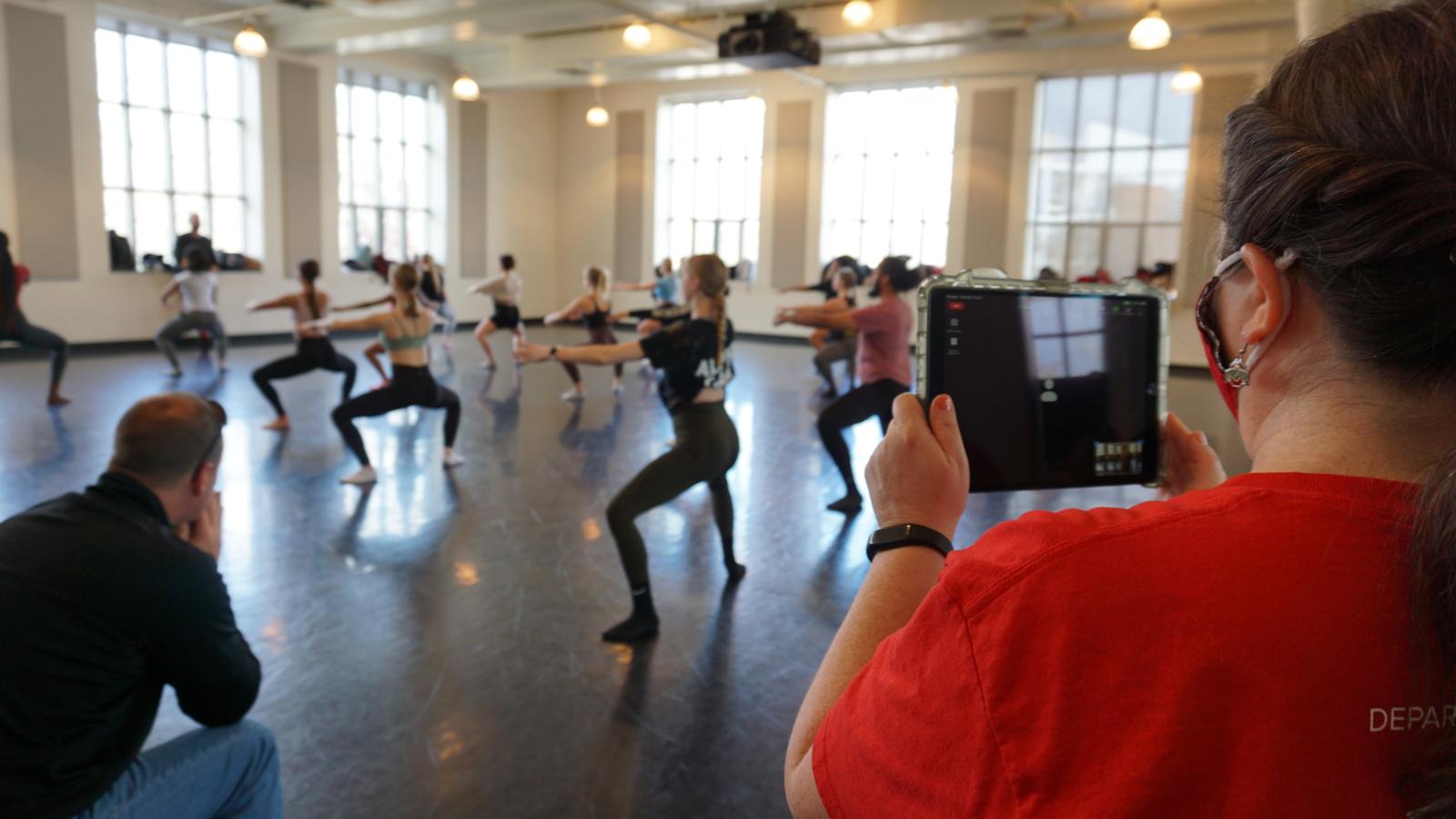 Dancers rehearsing in a studio while woman records