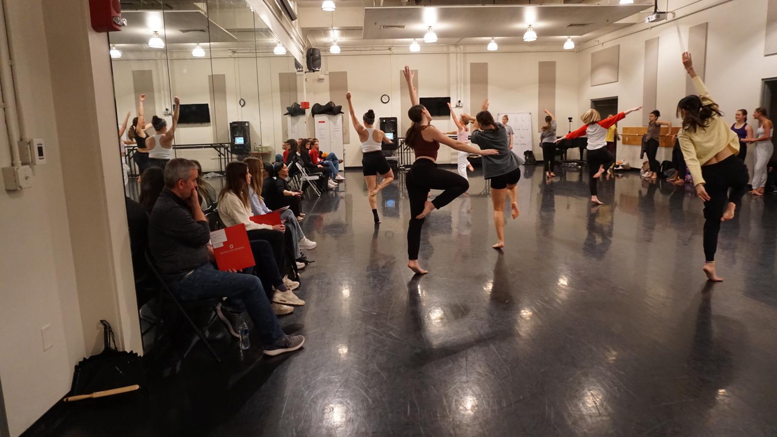 Dancers rehearsing in a studio with an audience