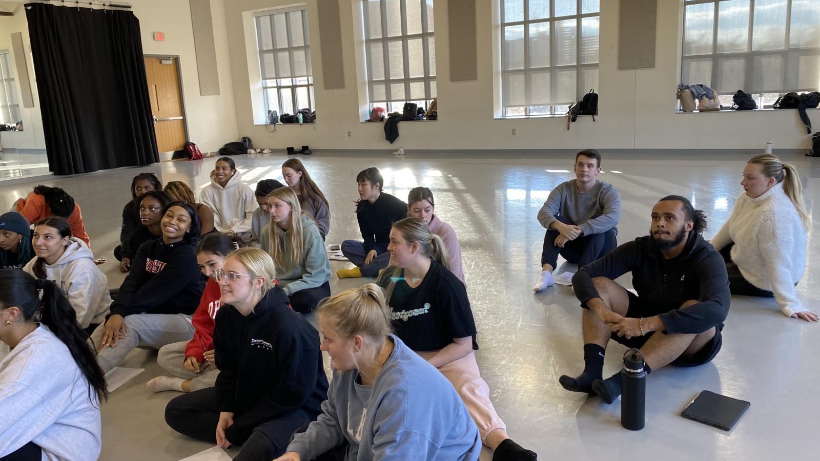 Students sitting on the floor of a dance studio