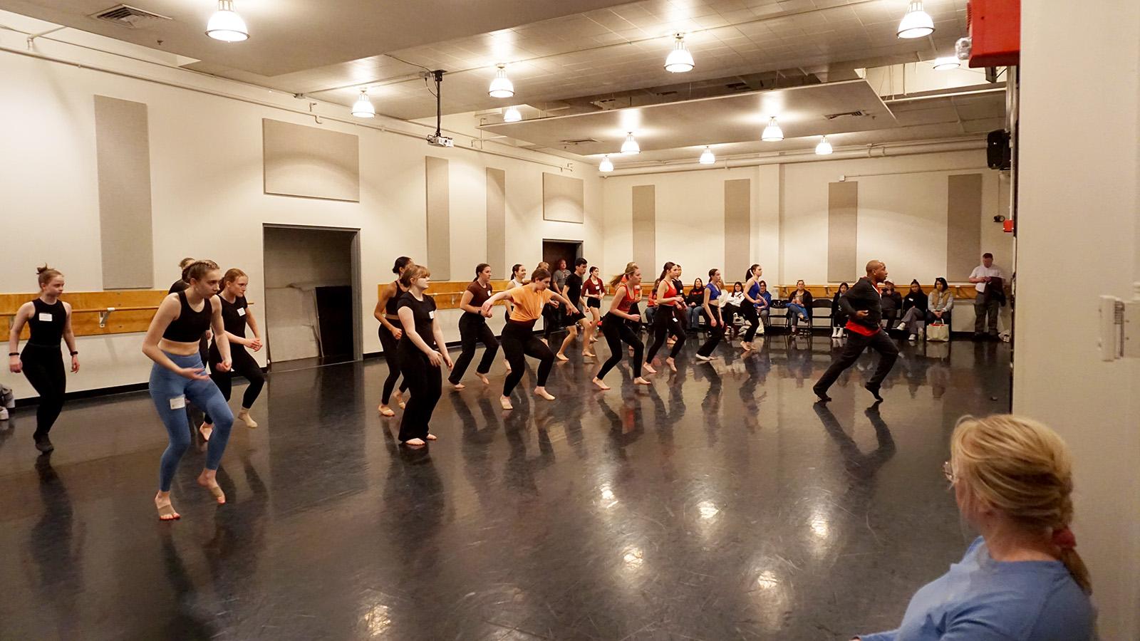 A group of dancers moving in a studio