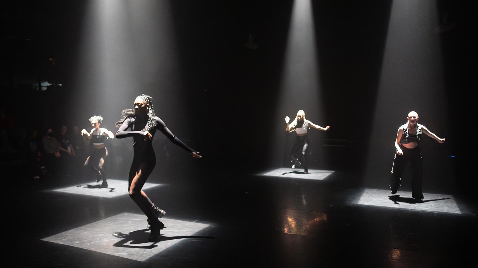 dancers wearing black on a lit stage