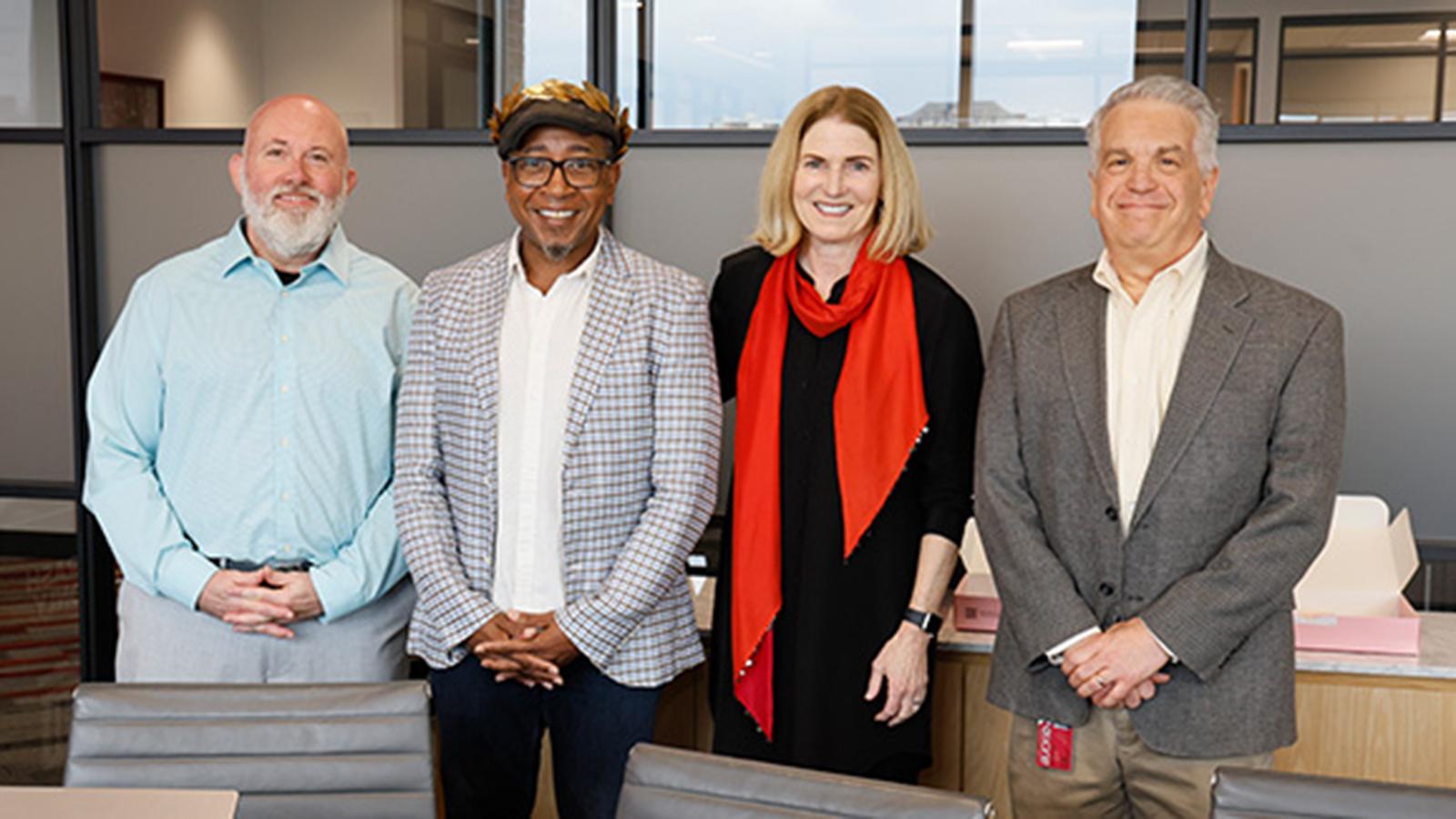Four people posing for a photo in an office