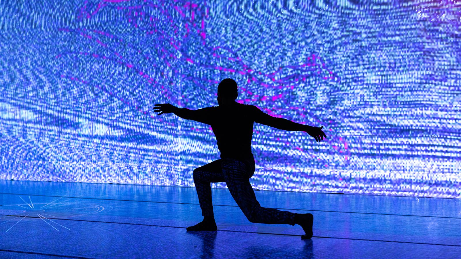 A dancer silhouetted in front of a blue screen