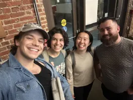 Four people posing for a photo in front of a brick wall